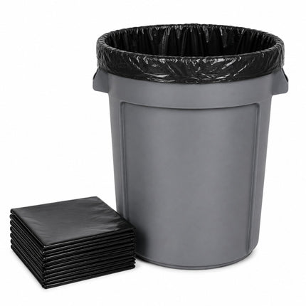 A gray plastic trash can with a black plastic liner inside, shown next to a stack of black square liners on a white background.