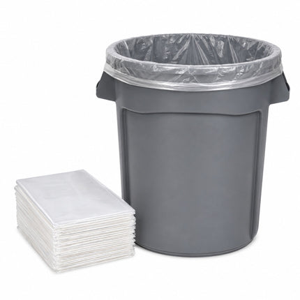 A dark gray plastic trash can with a clear plastic liner inside, shown next to a stack of clear plastic bag liners on a white background.