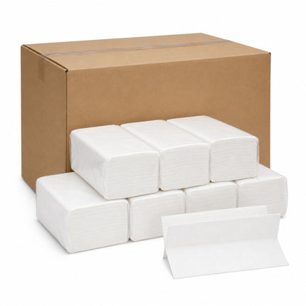 A bulk pack of white paper napkins with a stack of folded napkins in front and a large brown cardboard shipping box behind them, photographed on a clean white background.